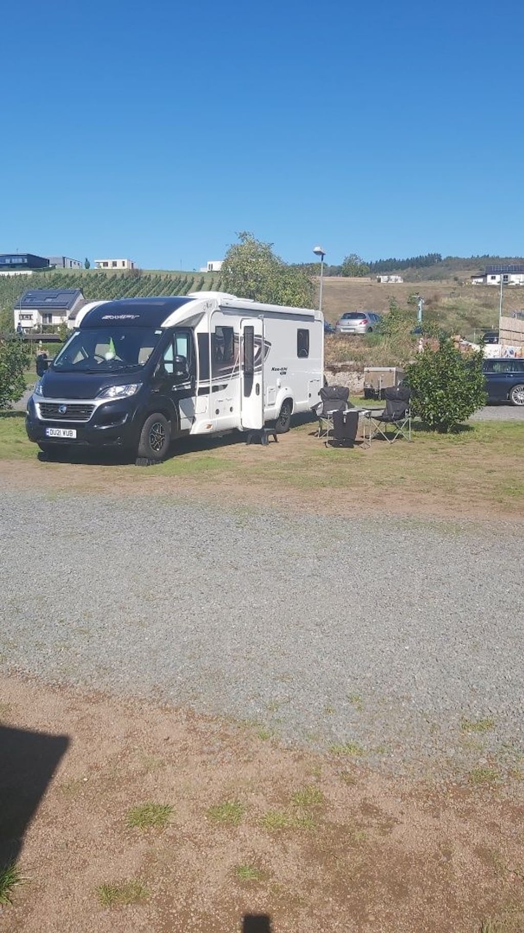 The Swift Kon-Tiki Sport 599 pitched on a sunlit hillside campsite with camping chairs out and green hills behind
